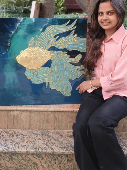 A student proudly displays the beautiful golden fish texture art she created in our professional class. This piece combines cone work, gold foil, and resin for a stunning 3D effect.