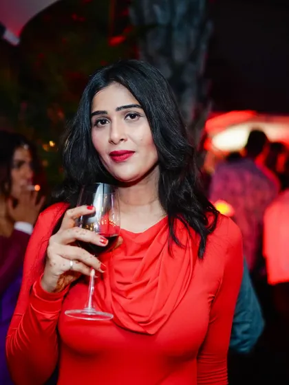 A guest enjoying a glass of red wine, perfectly matching the red-lit, spooky atmosphere.