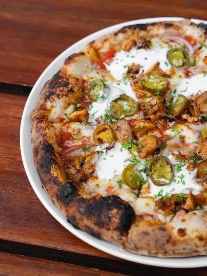Another look at the BBQ Chicken Pizza, showing the beautiful char on the crust and the even distribution of toppings.