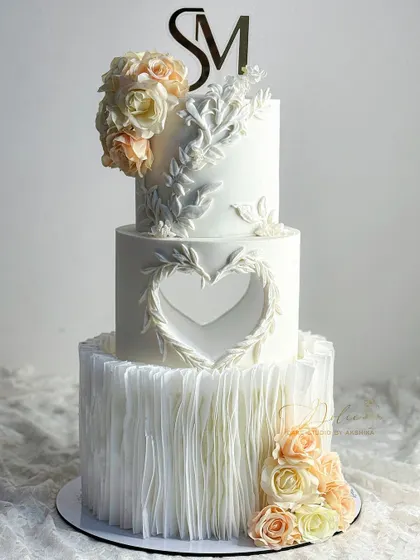 Elegance is in the details. This three-tier wedding cake features delicate wafer paper ruffles and intricate bas-relief details, techniques we can explore to elevate your cake designs.