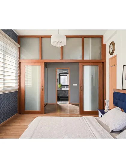 In the master bedroom, we created a walk-in wardrobe behind these large, sliding wooden doors with frosted glass, separating the sleeping area from the closet and bathroom.