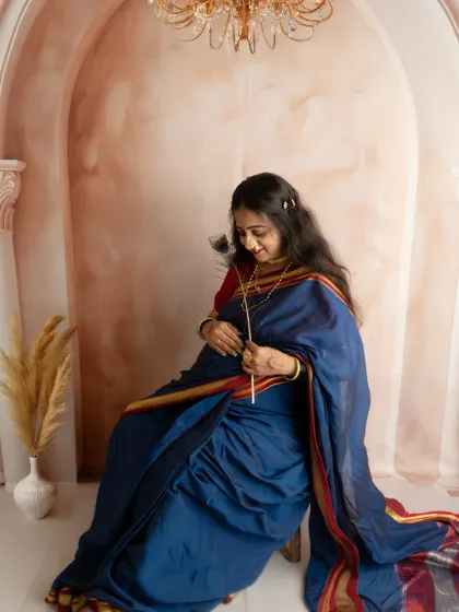 A contemplative pose, capturing the quiet joy of pregnancy. The rich fabric of the blue saree is highlighted by the soft studio lighting.
