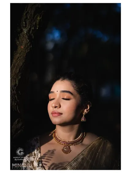 An artistic shot of Priyanka, with sunlight filtering through the trees. Her makeup looks ethereal and glowing, showcasing a peaceful and serene moment.