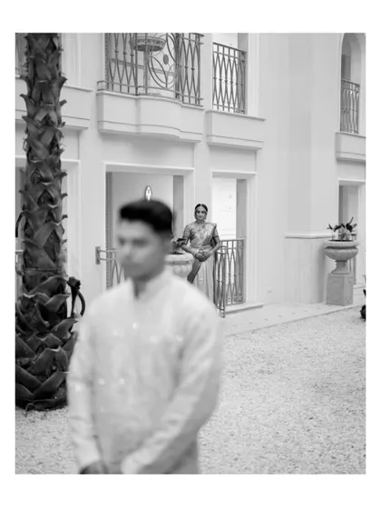 An artistic, out-of-focus shot of the groom with the bride in the background, creating a sense of anticipation and story.