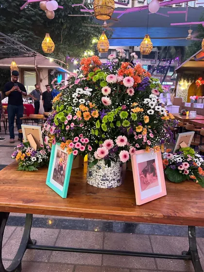 A beautiful floral centerpiece on a rustic wooden table, with framed baby photos adding a personal touch to this Bridgerton-inspired Godh Bharai.