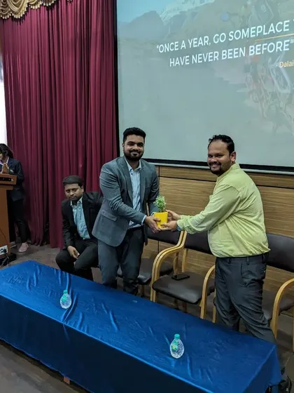 My co-founder receiving a token of appreciation, with our presentation slide in the background quoting the Dalai Lama: "Once a year, go someplace you have never been before."