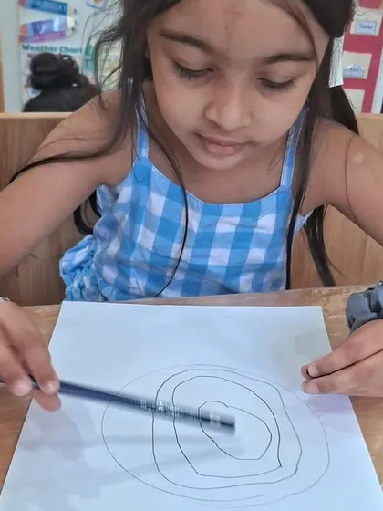With focused precision, a student traces circles for her Earth layers project. This simple action builds foundational skills for writing and drawing.
