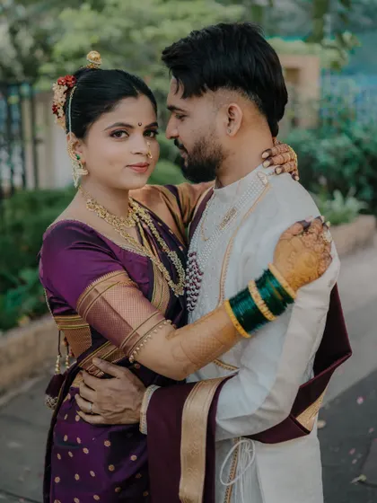 An intimate embrace that showcases the beautiful details of the bride's purple saree and traditional jewelry. This close-up captures the couple's connection and the richness of their wedding attire.