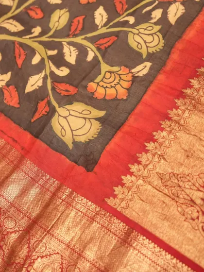 A captivating black Kanjivaram saree featuring a vibrant red border and exquisite, hand-painted Kalamkari artistry across the body.