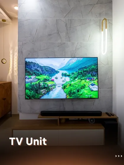 A minimalist TV unit that makes a statement. The combination of a marble-finish wall panel and a simple wood and white console creates a clean, modern aesthetic, perfect for contemporary homes.