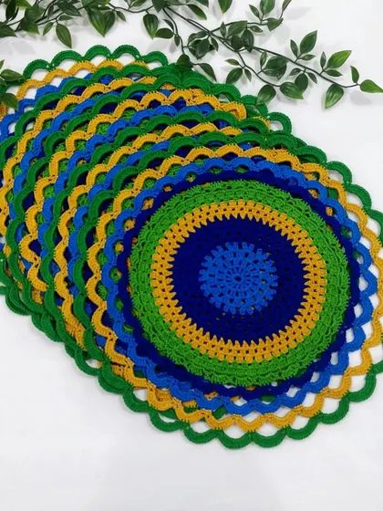 Another view of the stacked peacock placemats, highlighting the scalloped green border that finishes the design.