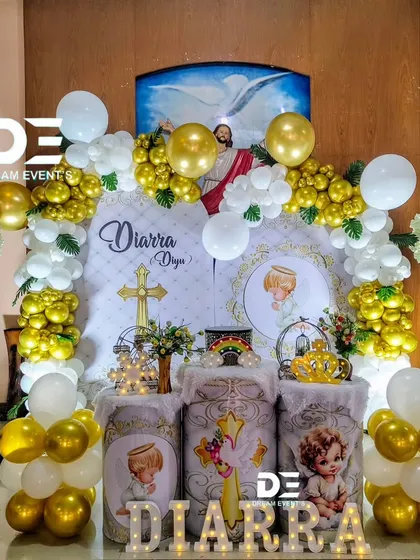 For baby Diarra's Christening, we designed this angelic theme with gold and white balloons, custom-printed pedestals, and marquee lights. The backdrop features an image of Jesus, adding a divine touch.