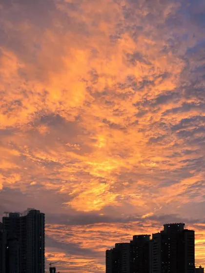A stunning cloud-filled sky is set ablaze with orange light during a Mumbai sunset, creating a textured and dramatic scene.
