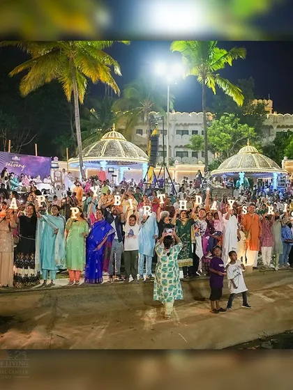 The community gathers to wish Gurudev a happy birthday, holding up letters in front of the amphitheater. It's a celebration filled with love, laughter, and heartfelt gratitude.