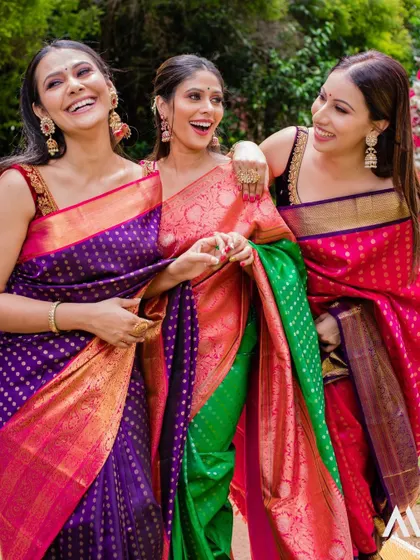 A moment of shared laughter between friends, all looking vibrant and beautiful in our Kanchipuram silk sarees.
