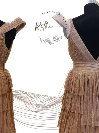The front and back view of the rose gold gown, highlighting the sculpted shoulders and deep V-back.