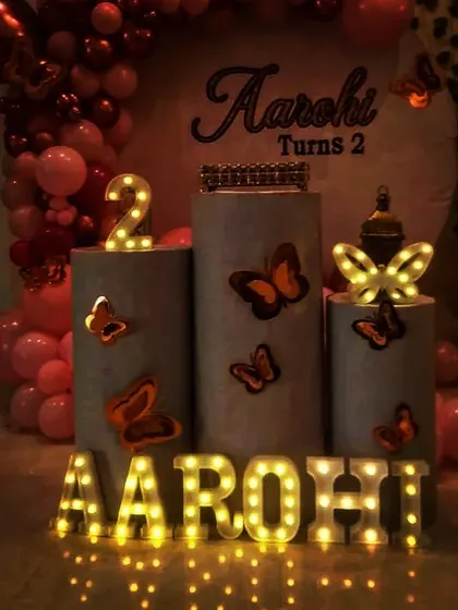 A close-up of a simple birthday setup, highlighting the illuminated marquee letters and butterfly details on the pedestals. This shows how small touches can make a big impact.