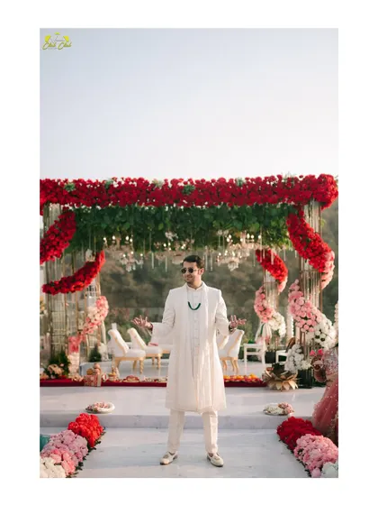 The groom stands ready at the mandap. This shot captures the impressive floral decor and the groom's anticipation, setting the stage for the ceremony.