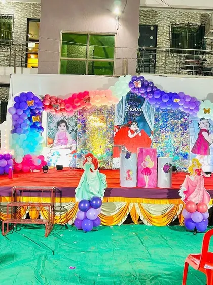 A full view of an outdoor princess-themed birthday party stage. I designed this setup with multiple character cutouts, a shimmering backdrop, and elaborate balloon garlands in pink, purple, and blue to create a magical kingdom for the birthday girl.