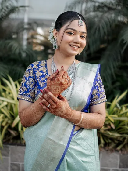 The bride showing off her henna-adorned hands. Her makeup is soft and pretty, letting her natural joy shine through.