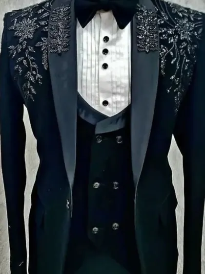 A black velvet three-piece tuxedo with heavy silver and black floral embroidery on the shoulders. This is a truly regal piece for a groom's reception.
