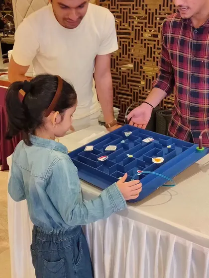 A young guest tests her steady hand at the buzz wire maze, a classic game that teaches about complete and incomplete circuits in a fun, challenging way.