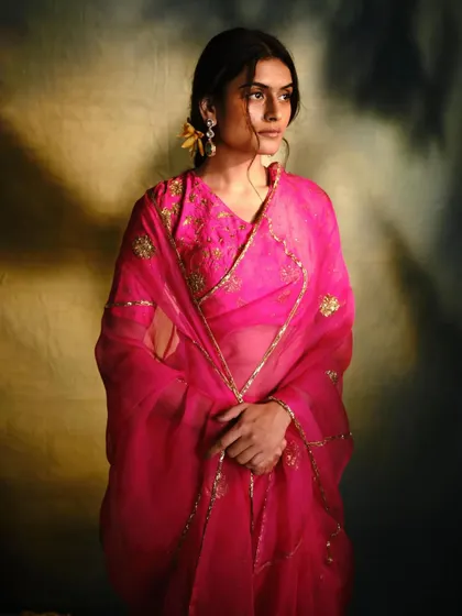 The sheer beauty of a fuchsia organza drape. This look is all about color and light, styled with a matching embroidered blouse for a cohesive and striking ensemble.