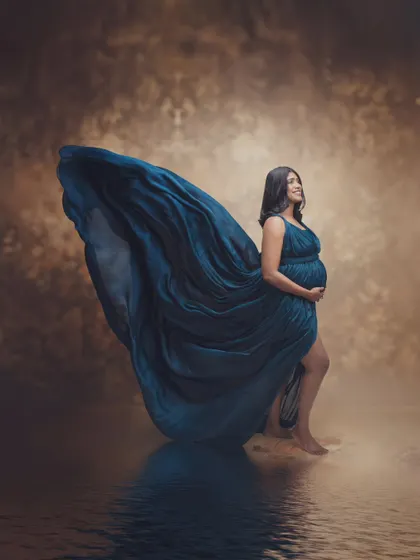 The essence of grace and power. This shot feels larger than life, capturing the powerful journey of motherhood in an artistic form with a flowing gown and water reflection.