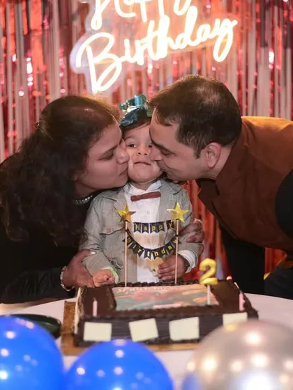 A heartwarming moment where the birthday boy gets kisses from his mom and dad during the cake cutting.