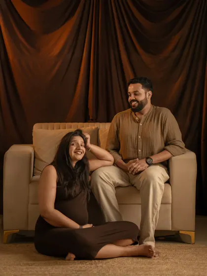 A candid and joyful moment between a couple in the studio. Her laughter and their relaxed poses show the genuine happiness of their pregnancy journey.