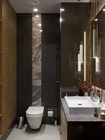 This compact bathroom features a floating vanity and a toilet, with a dramatic floor-to-ceiling marble-patterned tile. The space is cleverly designed with built-in wooden shelves and modern pendant lights for a functional yet luxurious feel.