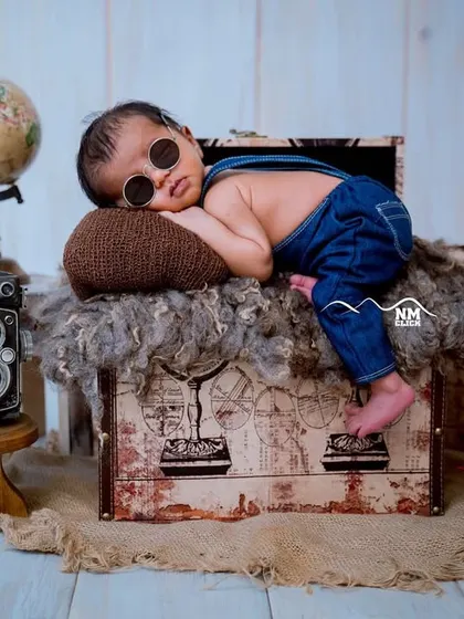 Dreaming of future adventures. This travel-themed newborn setup with a vintage suitcase, globe, and camera is a creative way to capture your sleeping baby.