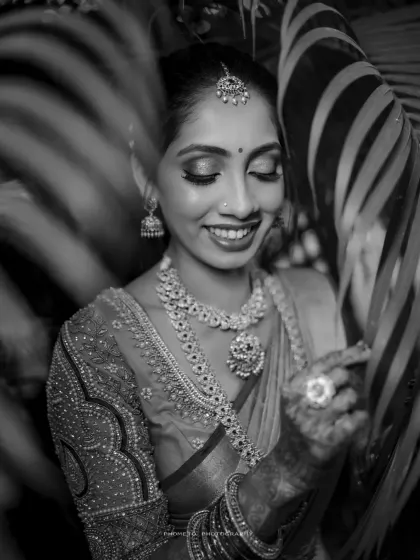 A stunning black and white portrait of the bride, her smile framed by leaves, adding an artistic touch.