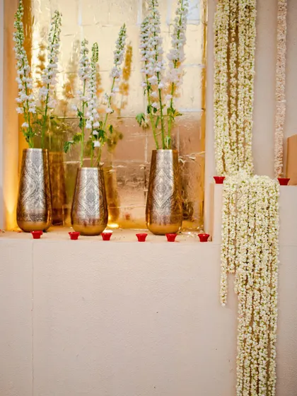 Traditional elements like jasmine garlands and brass vases with white tuberoses add fragrance and a sense of sanctity to the Jaimala stage.