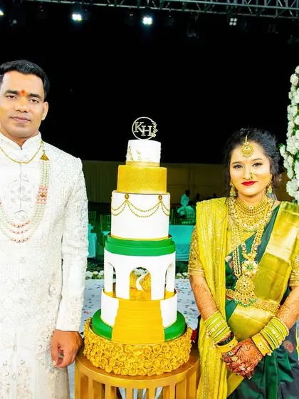 The couple poses for a photo with their grand engagement cake, a centerpiece that perfectly matches the scale of their celebration.