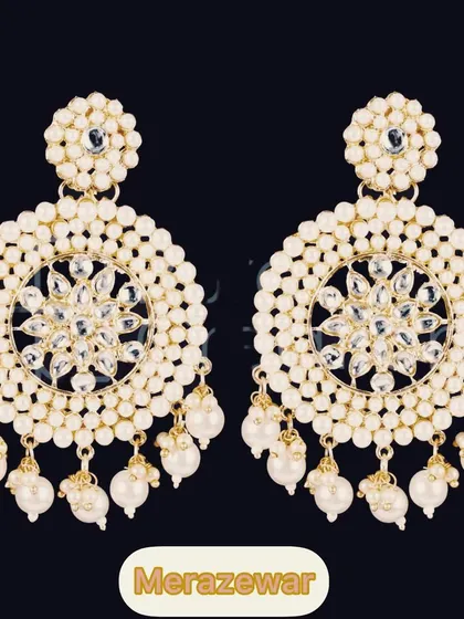 A classic and elegant choice. These large circular chandbalis are detailed with kundan work and surrounded by pearls, making them a timeless piece for any ethnic wardrobe.