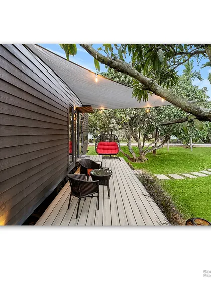 The wooden deck of a prefab home, complete with a cozy seating area and string lights. This shot captures the essence of relaxed outdoor living and the simple comforts of a modern cottage.