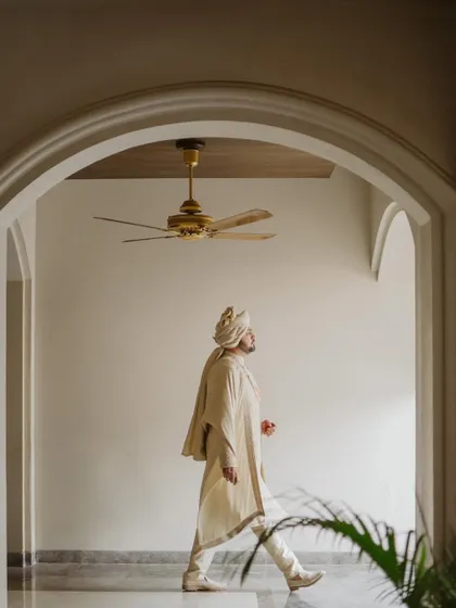 A stylish, architectural portrait of the groom in his sherwani, captured as he walks through an elegant corridor.