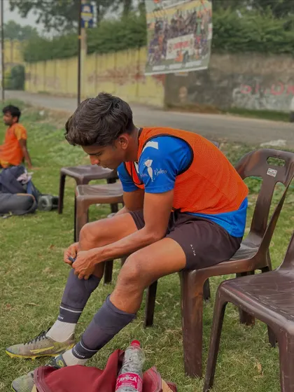A moment of rest and preparation. A player adjusts his gear on the sidelines, getting ready to get back into the action.