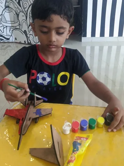 A focused young artist chooses his next color for the fighter jet project. Providing a range of colors allows for maximum creative expression.