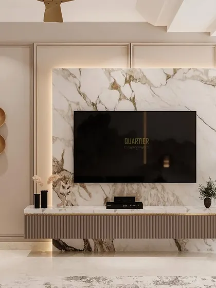 The TV unit in a guest bedroom, designed with a fusion of European and modern themes. The unit has fluted shutters and is set against a backdrop of marble texture and classic mouldings.