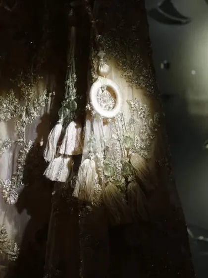 An artistic close-up of the bridal lehenga, with a spotlight highlighting the intricate embroidery and tassels. This detail shot showcases the craftsmanship and beauty of the bride's attire.