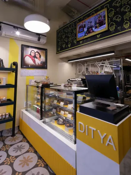 A wider view of the bakehouse counter, showing the display cases filled with treats. The design focuses on making the products the hero, with bright, clear lighting and an organized, accessible layout.