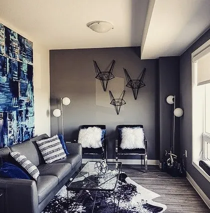 A moody and modern living room with dark grey walls. The choice of a dark, solid color for the main walls creates a sophisticated backdrop for the abstract art and decor.