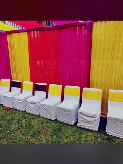 A simple and neat row of chairs with white covers and yellow sashes, ready for a Sangeet or Haldi function.