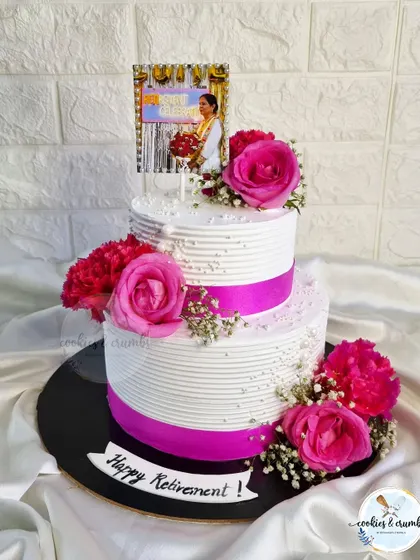 I created this two-tier floral cake for a retirement party on just a six-hour notice. It features clean lines, a pink ribbon, and is adorned with fresh roses and carnations for a classic, celebratory feel.