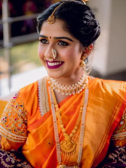A beautiful, smiling portrait of the Maharashtrian bride in her vibrant orange saree and traditional jewelry.