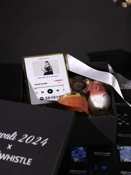 Inside the DIGIWHISTLE corporate hamper, featuring a personalized music plaque, Ferrero Rocher chocolates, and other curated items for a unique and modern gift.