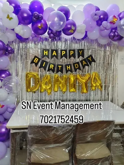 A pretty purple and white home decoration for a first birthday. The simple balloon arch over a shimmer curtain is an easy and beautiful way to celebrate at home.