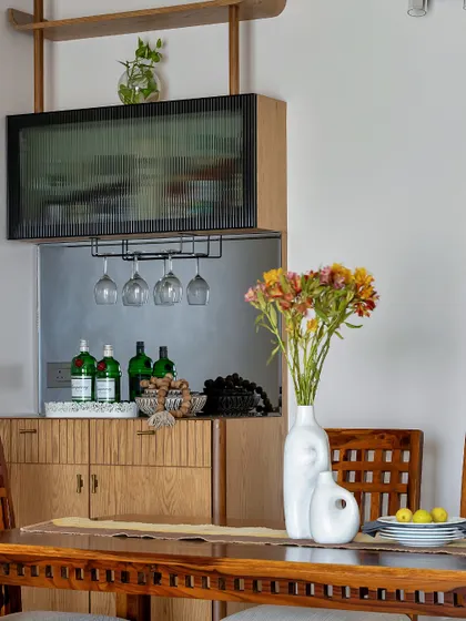 A close-up of a well-styled bar and dining area. Fresh flowers, colorful glassware, and a curated selection of drinks on a tray transform this functional corner into a beautiful feature for entertaining.